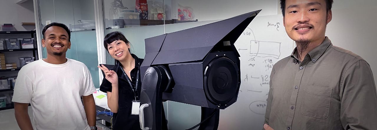 Three people taking a photo with a space telescope